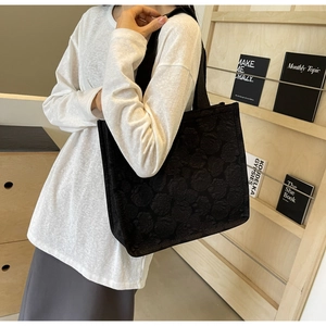 Détail de la texture jacquard florale noire d'un grand sac cabas porté par un mannequin