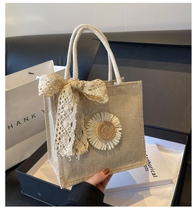 Détail du sac cabas beige tissé avec une fleur de soleil 3D et un nœud en dentelle
