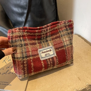Detail of red-brown checkered tweed cosmetic bag with vintage woven label and fabric texture