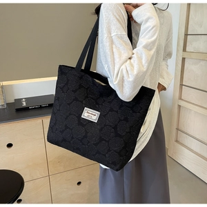 Close-up of black floral jacquard tote bag with elegant rose pattern and white woven label
