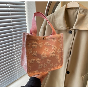 Detail of pink canvas tote featuring 3D floral textures and vintage metal snap button