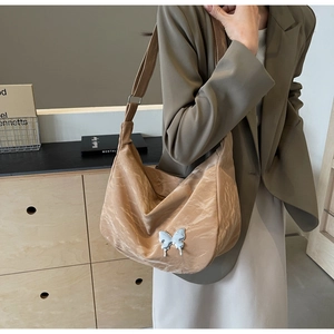 Détail du sac plissé marron clair avec boucle papillon argentée et bandoulière large