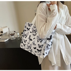 Close-up of lifestyle canvas tote bag featuring black butterfly print on white fabric