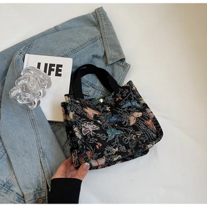 Top view of a black jacquard mini tote bag with colorful butterfly embroidery and magnetic buckle
