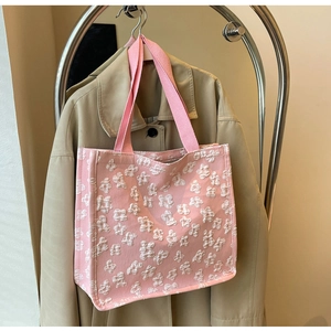 Detailed close-up of pink tote bag with 3D floral texture hanging on a khaki trench coat