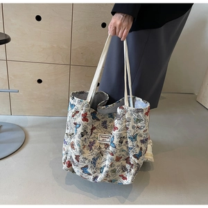 Detail of canvas tote bag featuring colorful butterfly prints and soft cotton rope handles