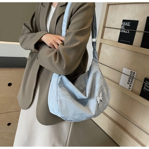 Détail du grand sac cabas plissé bleu clair avec pendentif papillon porté à l'épaule
