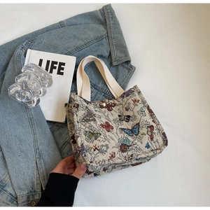 Detailed view of butterfly embroidery on canvas tote bag with cotton handles and metal snap