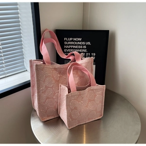 Détail du tissu jacquard rose à motif de roses et ensemble de sacs sur un support