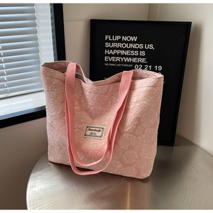 Detail of pink floral jacquard tote bag featuring rose relief texture and fabric logo label