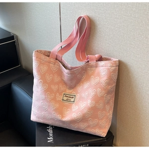 Close-up of pink tote bag featuring 3D heart jacquard embroidery and brand label