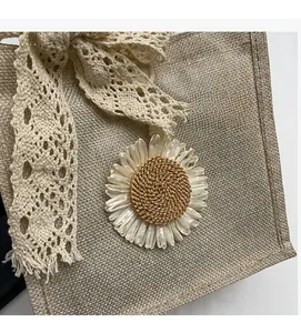 Close-up of jute tote bag featuring cream lace bow and handmade sunflower pendant detail