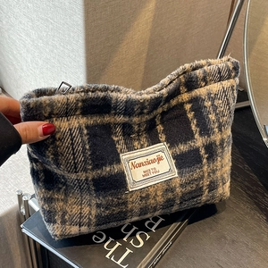 Detail of navy and brown plaid fabric texture and woven label on a cosmetic pouch