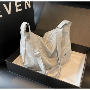 Détail du sac hobo argenté métallisé avec breloque papillon dans une boîte cadeau
