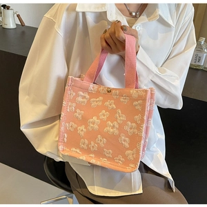 Detail of pink canvas tote bag featuring 3D white flower accents and gold metal buckle