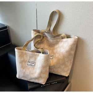 Detail of beige jacquard heart pattern on large and small tote bags in home setting