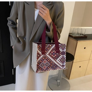 Detailed close-up of a beige canvas tote with colorful ethnic geometric embroidery patterns
