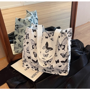 Close-up of a canvas tote bag featuring a realistic black butterfly print and reinforced straps