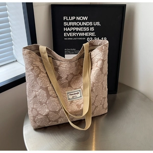 Detail of light brown canvas tote bag featuring textured 3D rose patterns and woven straps