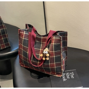Detail of red and grey checkered canvas tote bag featuring a cute plush doll charm