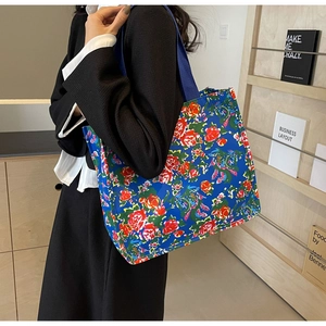 Side view of large tote bag featuring vintage vibrant floral prints and blue handles