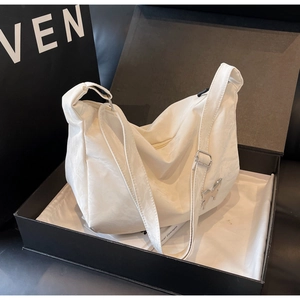 Gros plan d'un sac papillon blanc à texture plissée brillante dans sa boîte cadeau