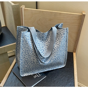Détail du sac cabas en toile bleu clair à motif floral sur une chaise en bois