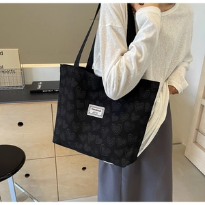 Detail of black tote bag with embossed heart textures and white label for daily commute