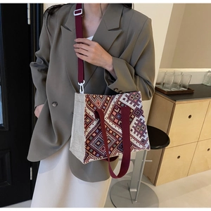 Detailed shot of ethnic woven tote bag with red handles on minimalist model outfit