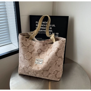 Detail of floral jacquard tote bag with textured rose patterns and wide shoulder straps
