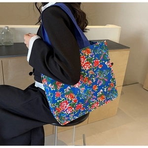 Détail du sac cabas en toile bleue à fleurs avec roses rouges et bandoulière large