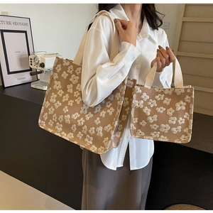 Detail shot of beige canvas tote set with white floral embroidery and webbing handles