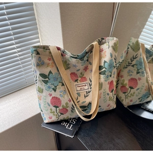 Detail of vintage floral jacquard tote bag with reinforced handles and woven brand label