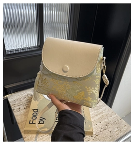 Détail du sac beige avec broderie de paysage et accessoire de pompon en soie