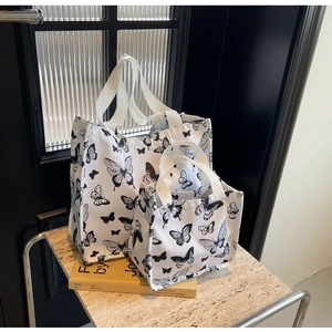 Two-piece white canvas tote bag set with black butterfly patterns on stone display stand