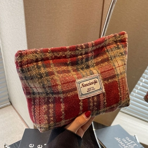 Detail of red and grey plaid textured fabric pouch with rectangular stitched label