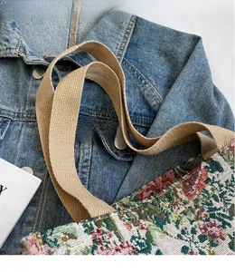 Close-up of floral jacquard tote bag with beige woven shoulder strap in casual setting