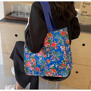 Détail du grand sac cabas en toile bleue avec des motifs de fleurs rouges
