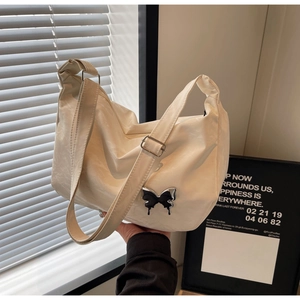 Détail d'un sac cabas en cuir texturé blanc cassé avec un ornement de papillon