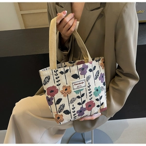 Detailed close-up of a canvas tote bag featuring colorful woven floral patterns and tag