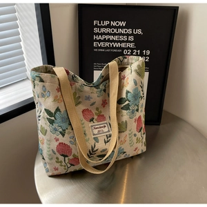 Detail of floral canvas tote bag with woven handles and vintage print pattern