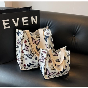 Detailed view of two different sized off-white canvas tote bags with colorful butterfly prints