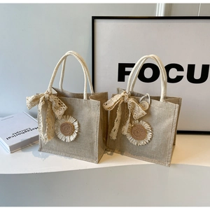 Détail d'un sac en lin avec tournesol tissé et nœud en dentelle sur tissu texturé