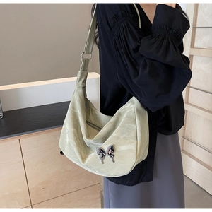 Détail du sac bandoulière vert clair avec ornement métallique en forme de papillon