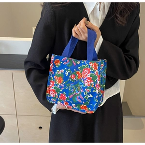 Détail d'un sac en toile bleu roi avec imprimé floral et bouton-pression en métal doré