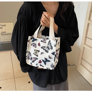 Detail of canvas tote bag with butterfly prints held by a model in a cozy interior