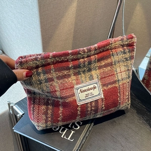 Detail of red and white checkered tweed makeup bag with zipper and woven label
