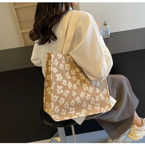 Detail of floral embroidery and high-capacity canvas tote bag shown on model