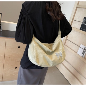 Détail d'un sac bandoulière vert clair en tissu texturé avec boucle papillon argentée