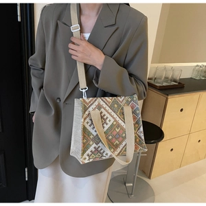 Detail of woven crossbody bag with geometric patterns and beige shoulder strap on a model